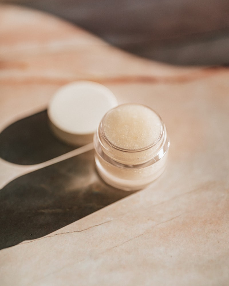Sleek modern skincare dropper bottle resting on a raw dark stone slab surrounded by shadows, minimalist dark aesthetic, luxury branding, no people, still life